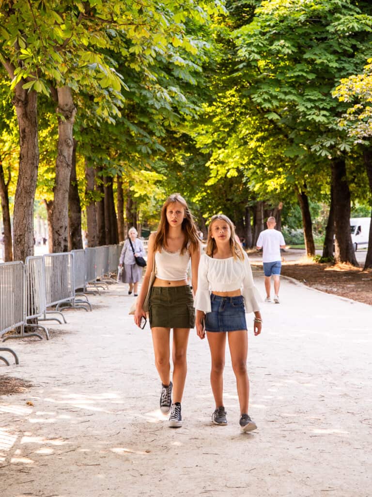 Two girls walking through a park.